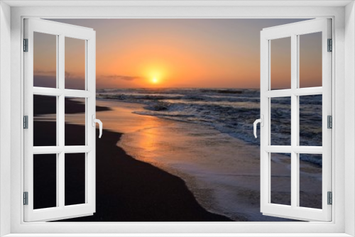Fototapeta Naklejka Na Ścianę Okno 3D - Amanecer en la playa, observándose en el horizonte la salida del sol y un bonito cielo con diferentes tonalidades que se reflejan en el agua de la orilla del mar