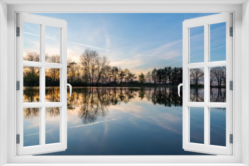 Fototapeta Naklejka Na Ścianę Okno 3D - Evening landscape with several trees on side of pond