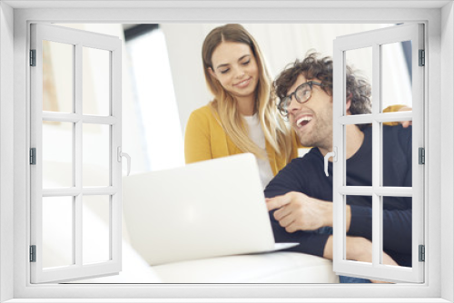 Shopping online. Shot of a lovely young couple relaxing on the couch and using a laptop at home