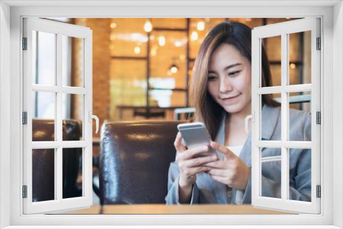 An Asian business woman holding and using smart phone in modern cafe