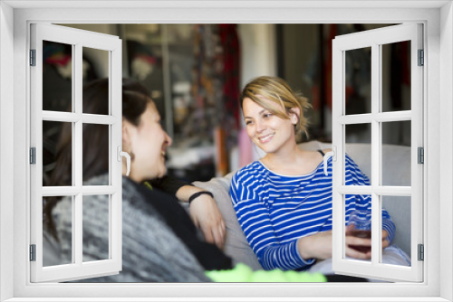 People relations. Two girls are speaking with emotions sitting on sofa