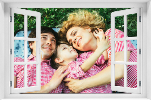 Unique perspective of happy european family smiling while lying down on the green grass in the park