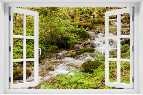 Fototapeta Naklejka Na Ścianę Okno 3D - A Small Waterfall Flowing through the Forest