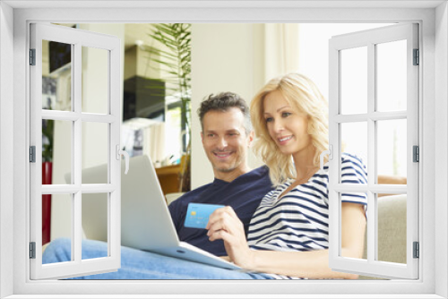 Buying online. Shot of a happy mature couple buying online with their credit card at home. 