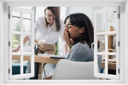 Young african american businesswoman laughing at colleague working behind