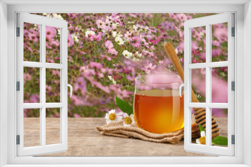 Fototapeta Naklejka Na Ścianę Okno 3D - Honey Bee in glass jar with honey dipper and flowers on the wooden table, flower garden background at sunrise or sunset