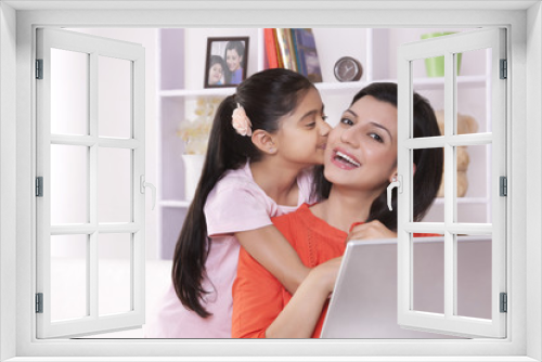 Portrait of mother getting kiss from daughter