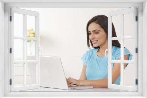 Beautiful young woman working on laptop at home