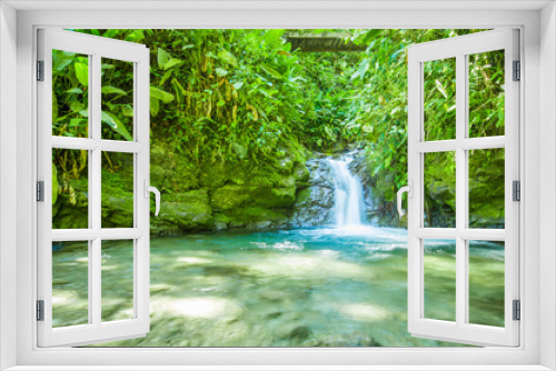 Fototapeta Naklejka Na Ścianę Okno 3D - Beautiful small waterfall located inside of a green forest with stones in river at Mindo