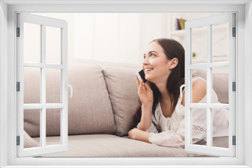 Young girl talking on mobile lying on sofa