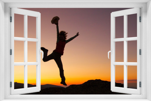 Fototapeta Naklejka Na Ścianę Okno 3D - Silhouette of happy joyful young attractive woman jumping and having fun at the mountain against the sunset. Freedom, adventure and leisure vacation concept.
