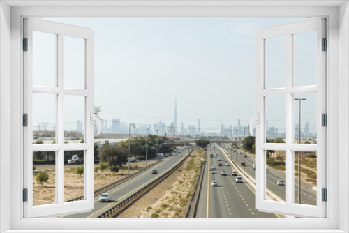 Fototapeta Naklejka Na Ścianę Okno 3D - Main road with desert and electricity posts and silhouette buildings in background at Dubai. 