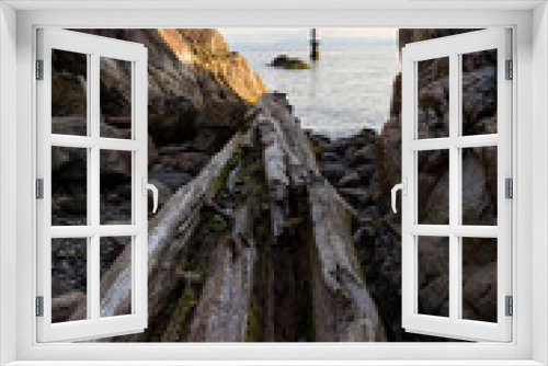 Fototapeta Naklejka Na Ścianę Okno 3D - Landscape view on the logs laying on the rocky shore between the cliffs. Picture taken in Whytecliff Park, West Vancouver, British Columbia, Canada, on a beautiful sunny day.