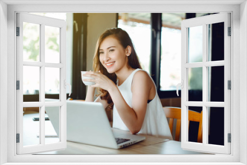 Beautiful Asia woman using laptop and drinking coffee at cafe