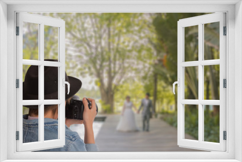 Fototapeta Naklejka Na Ścianę Okno 3D - Portrait  of wedding photographer in action,  attractive young woman shooting pictures wedding at park. This image for behind the scenes concept.