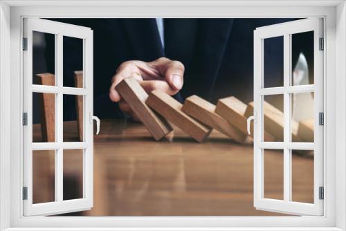 Fototapeta Naklejka Na Ścianę Okno 3D - Close up of businessman hand Stopping Falling wooden Dominoes effect from continuous toppled or risk, strategy and successful intervention concept for business