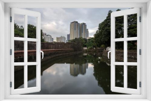 Fototapeta Naklejka Na Ścianę Okno 3D - View of the canal with water against the backdrop of the cityscape with trees and buildings. 