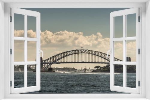 Fototapeta Naklejka Na Ścianę Okno 3D - Sydney, Australia - March 26, 2017: Frontal view of black metalic Harbour Bridge including support towers on both sided seen off water under cloudscape. Denison Fort in bay and multiple small boats.