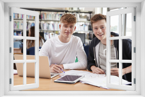 Two Male College Students Collaborating On Project In Library