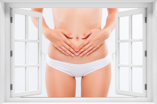 Concept of early term of pregnancy. Close up cropped photo of woman's abdomen and belly button, she is touching her slim stomach with two hands,girl wear panties, isolated on white background