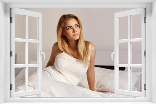 Pretty blonde wakes up lying in the white bed