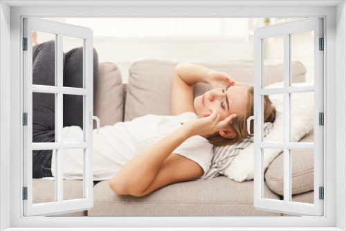 Casual blonde girl feeling pain while lying on the couch