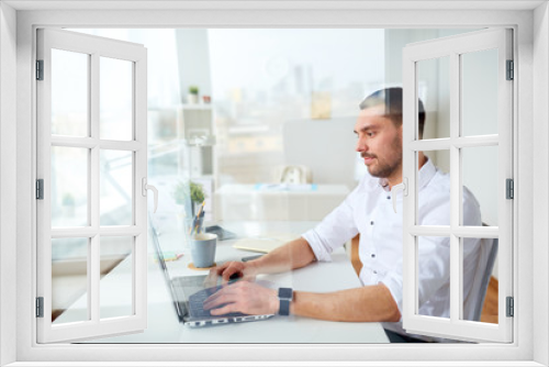 happy businessman typing on laptop at office