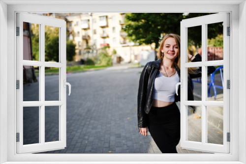 Elegant blonde girl wear on black leather jacket posing at streets of town.