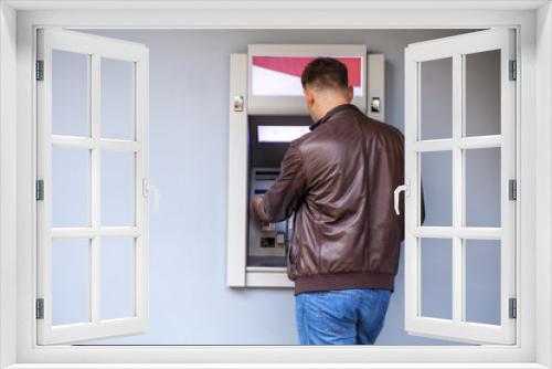 Young man inserting a credit card to ATM