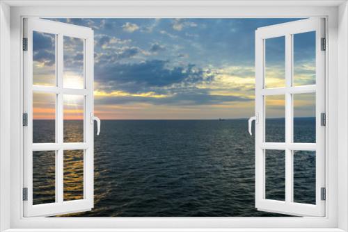 Fototapeta Naklejka Na Ścianę Okno 3D - Picturesque sea landscape - the sun rises over the sea against a cloudy sky and in the distance you can see the ship and land.