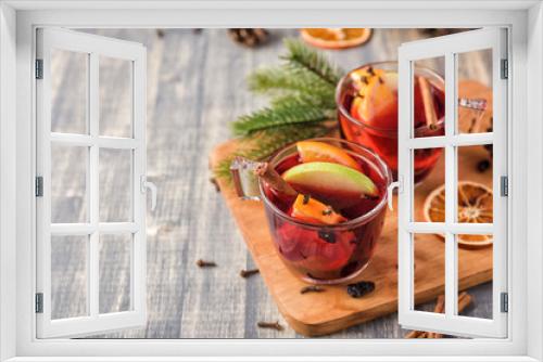 Fototapeta Naklejka Na Ścianę Okno 3D - Christmas mulled wine on wooden background. Hot alcohol drink with sliced oranges and apple. Fir-tree branches, cinamon, cloves