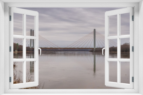 Fototapeta Naklejka Na Ścianę Okno 3D - Water landscape with the suspension bridge across the Vistula river and its reflection in water under the cloudy sky