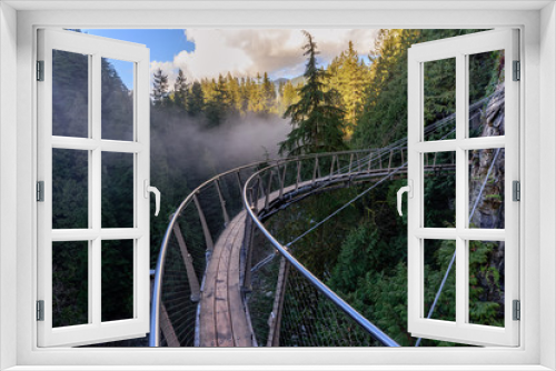 Fototapeta Naklejka Na Ścianę Okno 3D - a view from above from the suspension bridge on rough streams of a mountain river among green forests and rocky mountains