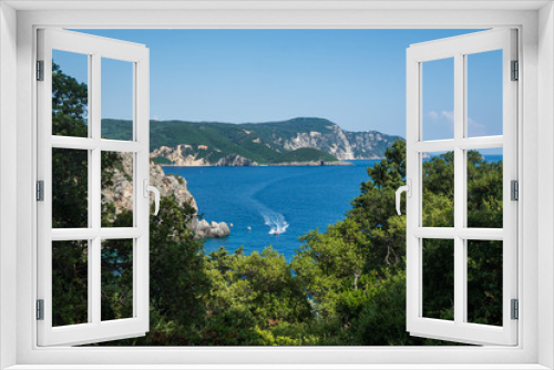 Fototapeta Naklejka Na Ścianę Okno 3D - Scenic view on the Ionian sea through the trees. Speedboat sails on the sea.
