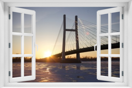 Fototapeta Naklejka Na Ścianę Okno 3D - The sun reflecting off a bridge at sunrise over a river