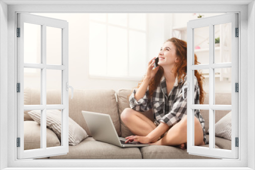 Girl with laptop and mobile sitting on beige couch.