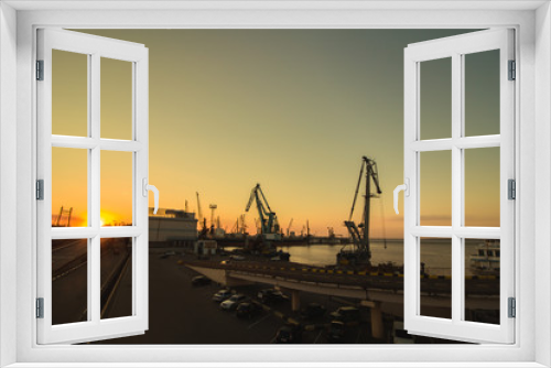 Fototapeta Naklejka Na Ścianę Okno 3D - Industrial photo of busy port in the city. Sunset over the sea and cargo ships. Yellow sun and deep water. Romantic photo harbor.