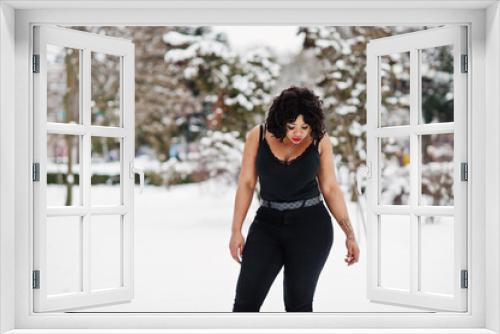 Stylish african american plus size model with mobile phone at hand  at winter snowy day.