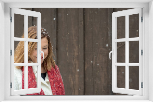 beautiful woman standing outside brown wood barn with fresh snow falling