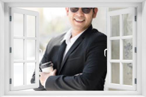 Asian modern businessman holding coffee cup and standing along the building, lifestyle concept.
