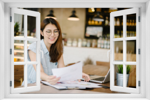 Concentrated at work. Confident young woman in smart casual wear working on laptop while sitting near window in creative office or cafe