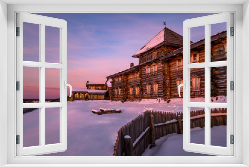 Fototapeta Naklejka Na Ścianę Okno 3D - traditional log house. the facade of the building against the evening sky in winter. wooden fence and snow in the yard