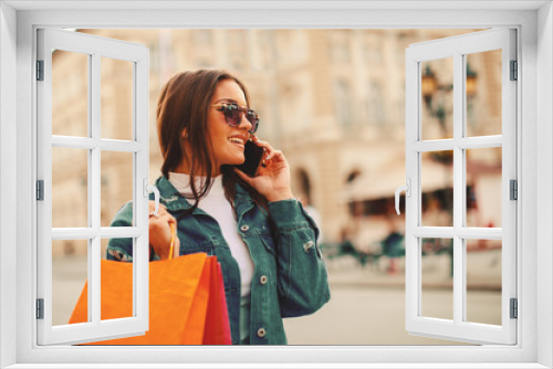 Beautiful young woman talking on the phone in the city after shopping