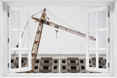 Fototapeta Naklejka Na Ścianę Okno 3D - Incomplete construction of a cement building on a construction site with a crane
