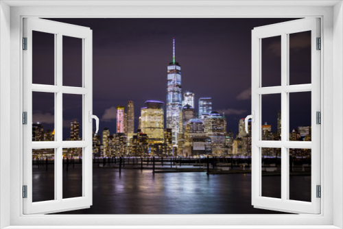 Fototapeta Naklejka Na Ścianę Okno 3D - The lights of Lower Manhattan and the World Trade Center reflect off the water of the Hudson River, as seen from Hoboken, New Jersey.