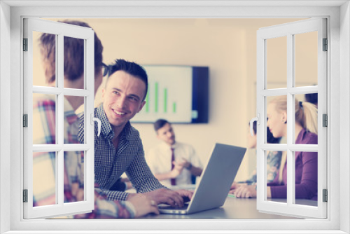 young business couple working on laptop, businesspeople group on meeting in background