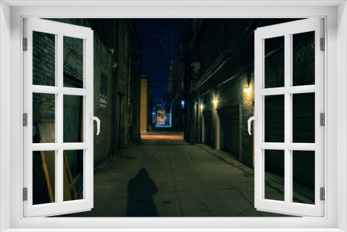 Fototapeta Naklejka Na Ścianę Okno 3D - Shadow of a person in a dark city alley at night