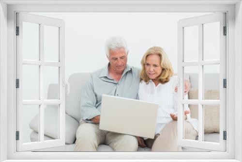 Relaxed senior couple using laptop at home