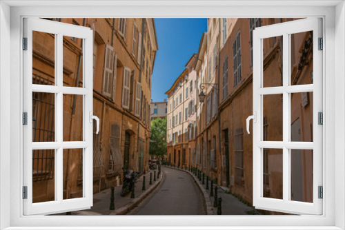 Fototapeta Naklejka Na Ścianę Okno 3D - Narrow alley with tall buildings in the shadow in Aix-en-Provence, a pleasant and lively town in the French countryside. Located in Bouches-du-Rhone department, Provence region, southeastern France