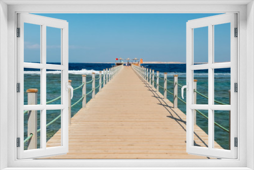Fototapeta Naklejka Na Ścianę Okno 3D - View of a wooden pier on the tropical seashore with blue sky and sea.